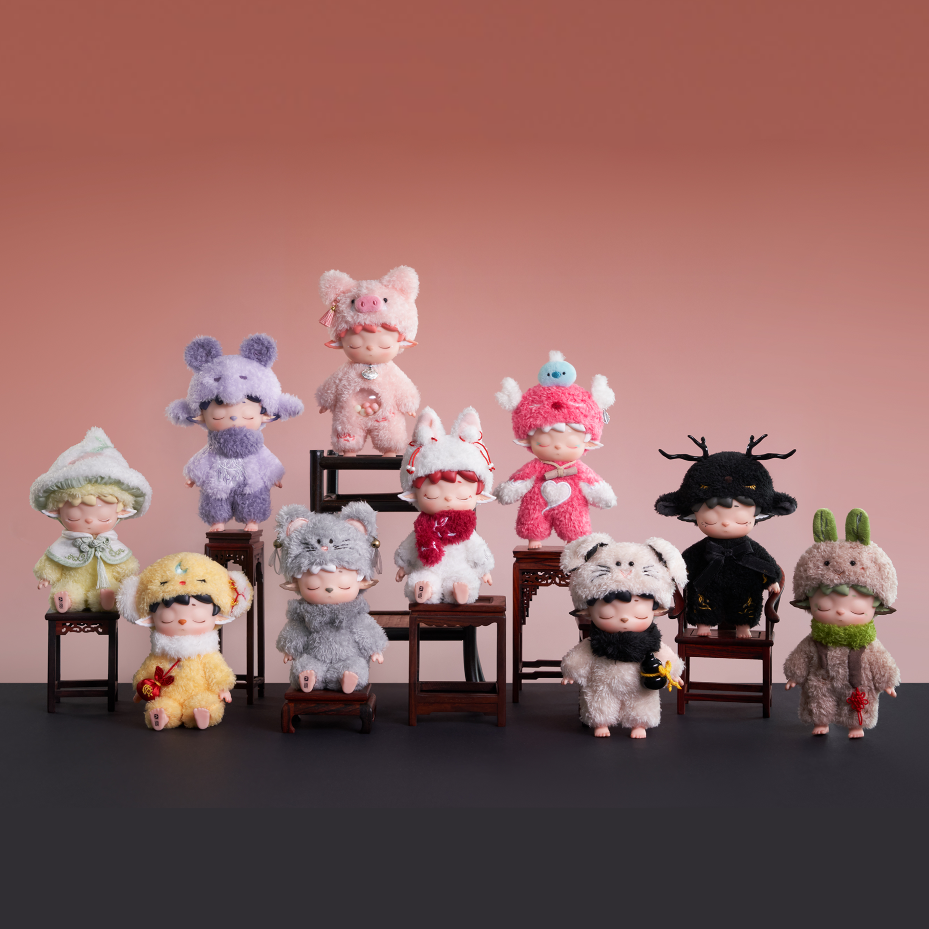 Row of small plush toys with various designs on a pink background