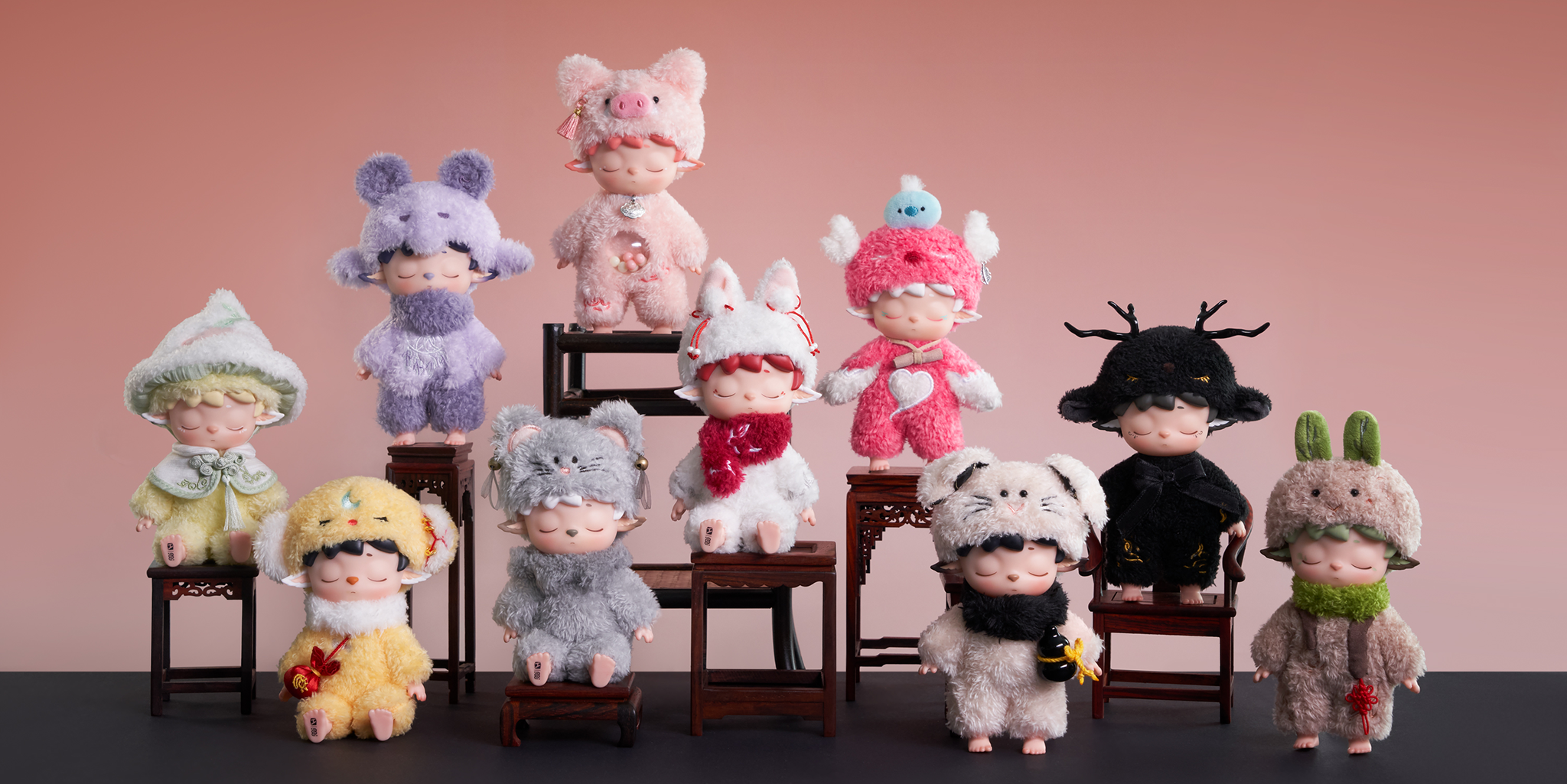 Row of stuffed toys in various outfits on a pink background